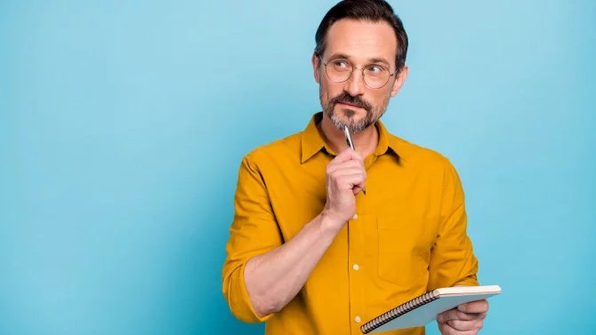 https://www.finance.cz/images/Muž v brýlích a propiskou u brady a diářem v druhé ruce přemýšlí